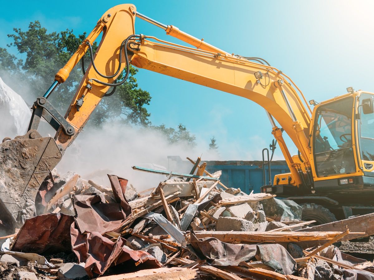 Excavator with a hydraulic breaker bringing down a structure into a pile of rubble