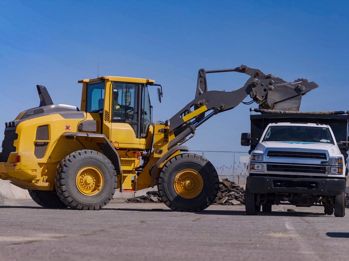 Wheel loader tipping spoil into the bed of a dump truck on a jobsite