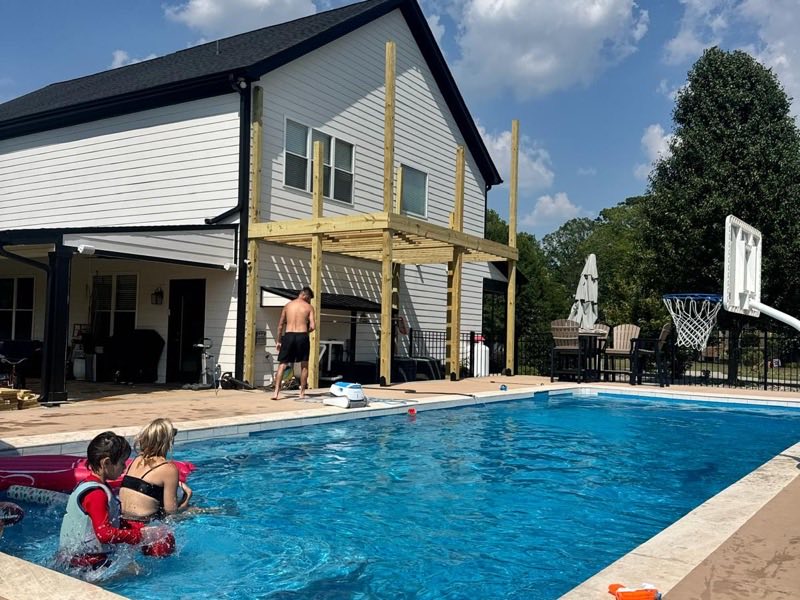 Timber posts and beams framed for an elevated deck beside a swimming pool