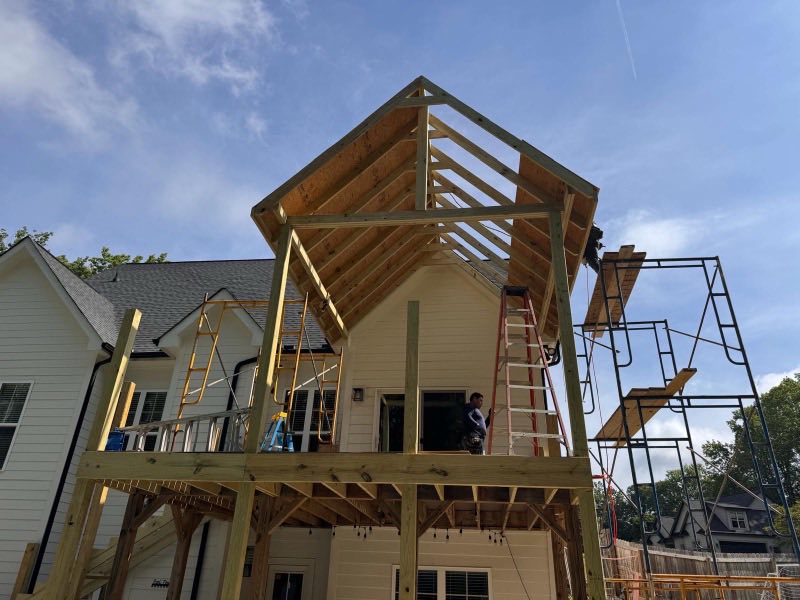 New gable porch roof framed in bare lumber against an existing house