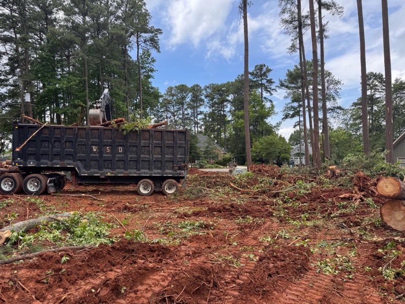 Dump truck loaded with brush and timber on a freshly cleared red clay lot