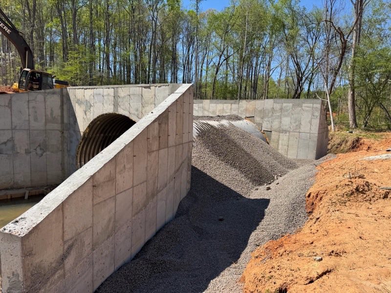 Concrete headwall and pipe culvert set into a bank with stone backfill