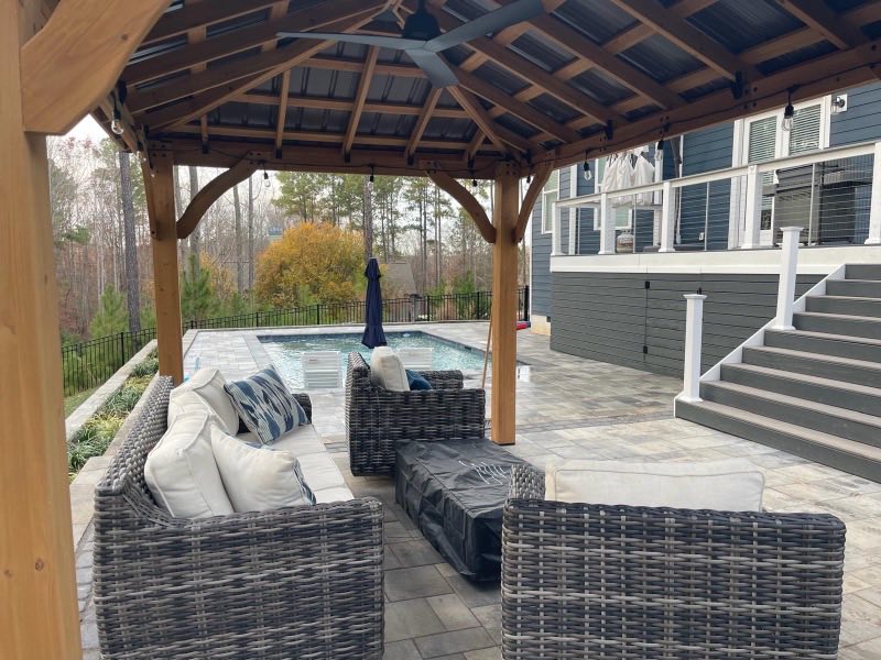 Timber pergola over a paver patio with seating beside a house